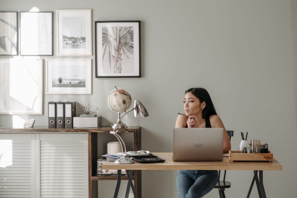 Femme pensive à son bureau illustrant le syndrome de l'imposteur et le doute sur ses compétences